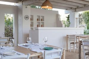 uma sala de jantar com mesas brancas e cadeiras brancas em Masseria Li Foggi em Gallipoli