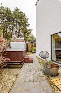 un patio trasero con bañera de hidromasaje junto a una casa en Bed & breakfast Duna met hammam, jacuzzi, sauna en Koksijde