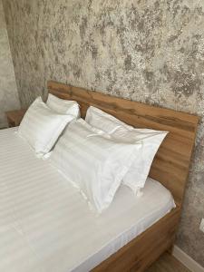 Una cama con sábanas blancas y almohadas. en Уютная квартира недалеко от Аэропорта, en Kostanái