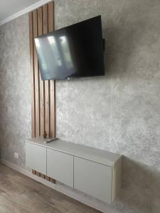 TV de pantalla plana colgada en la pared en Уютная квартира недалеко от Аэропорта, en Kostanái