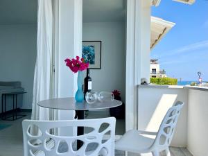 a table with a vase of flowers and two chairs at Vistas Del Mar by Hello Homes Sitges in Sitges