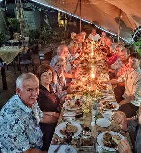 Un groupe de personnes assises à une longue table dans l'établissement OppiePlaas Country Estate, à Haga-Haga