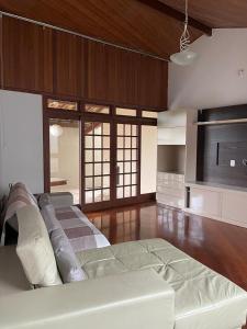Pousada Verde Villas في برومادينهو: غرفة معيشة كبيرة مع أريكة بيضاء وأرضيات خشبية