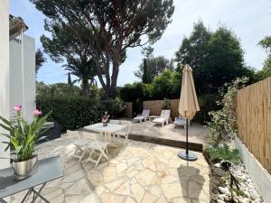 un patio con mesa y sombrilla en Appartement 1ch avec terrasse et jardinet à 400m de la plage, en Cavalaire-sur-Mer