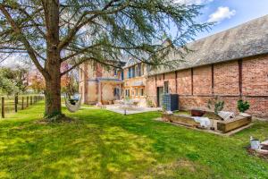 Maison Adeli - SPA- Braséro-Billard- Netflix-Wifi في Dozulé: مبنى من الطوب القديم مع شجرة في الفناء