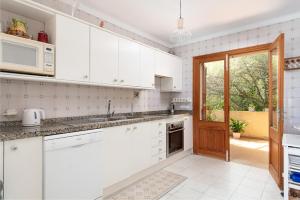 a white kitchen with white cabinets and a door at La Casa del Far in Alcanada +15 photos