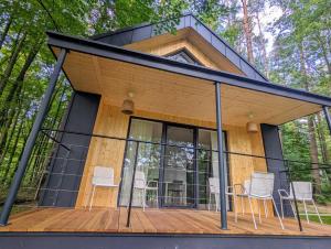 ein Haus im Wald mit einer Terrasse und Stühlen in der Unterkunft Kaletka - cisza i przyroda in Iława