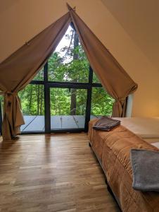 um quarto com uma cama e uma grande janela em Kaletka - cisza i przyroda em Iława