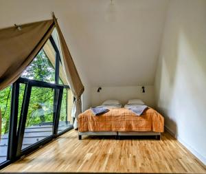 1 dormitorio con cama y ventana grande en Kaletka - cisza i przyroda en Iława