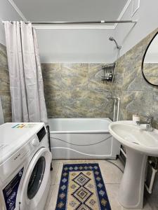 y baño con lavadora y lavamanos. en Уютная квартира недалеко от Аэропорта, en Kostanái