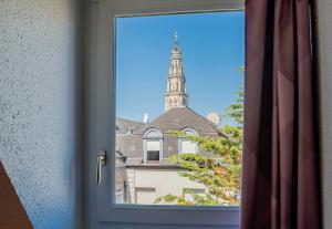 ein Fenster mit Blick auf ein Gebäude mit einem Uhrturm in der Unterkunft B&B HOTEL Arras Centre Les Places in Arras