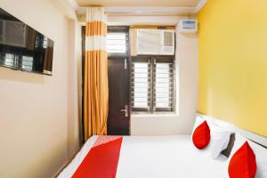 - une chambre avec un lit doté d'oreillers rouges et une fenêtre dans l'établissement Ishwar Niwas Residency, à Gurgaon