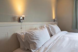 a bed with white sheets and pillows on it at The Harnser in Cley next the Sea