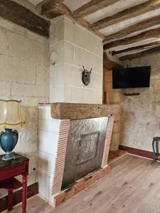 a living room with a brick fireplace with a tv at Moulin de Galerne, Le gite du Meunier in Seigy