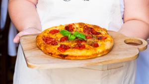 a woman holding a pizza on a cutting board at Palazzo Zacà in Gallipoli