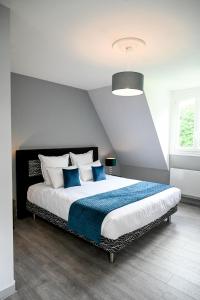 a bedroom with a large bed with blue pillows at La Fontaine Dort in Tessy-sur-Vire