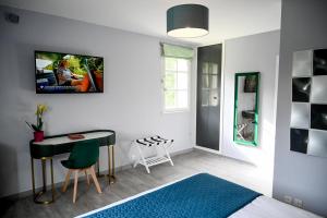 a bedroom with a bed and a desk and a table at La Fontaine Dort in Tessy-sur-Vire