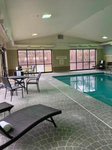 - une piscine avec une table et des chaises dans un bâtiment dans l'établissement Holiday Inn Express - Akron NW - Fairlawn, an IHG Hotel, à Akron