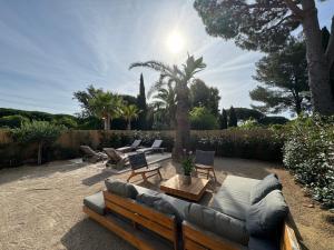 a patio with a couch and chairs and palm trees at Appartement 3ch avec terrasse et jardin à 400m de la plage in Cavalaire-sur-Mer