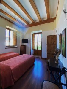 um quarto com uma cama, uma mesa e janelas em HOTEL EL RASTRO - Palacio Duque de Tamames - em Ávila