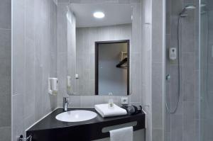 uma casa de banho com um lavatório, um chuveiro e um espelho. em B&B HOTEL Wien-St-Marx em Viena