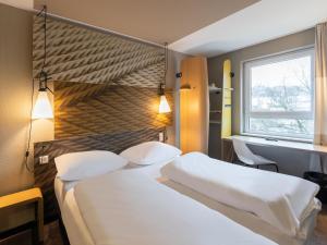 ein Hotelzimmer mit 2 Betten und einem Fenster in der Unterkunft B&B HOTEL Wuppertal-City in Wuppertal
