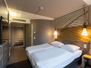 ein Schlafzimmer mit einem großen weißen Bett mit zwei Kissen in der Unterkunft B&B HOTEL Wuppertal-City in Wuppertal