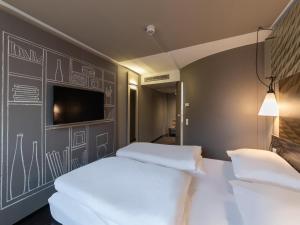 a bedroom with two beds and a tv on a wall at B&B HOTEL Wuppertal-City in Wuppertal