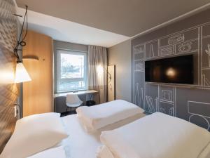 a hotel room with two beds and a flat screen tv at B&B HOTEL Wuppertal-City in Wuppertal