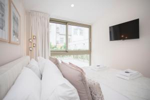 Cette chambre blanche dispose d'un lit et d'une fenêtre. dans l'établissement Liiiving in Porto - Soho Urban Retreat, à Porto