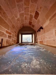 a large pool of water in a room with a window at Tre Archi Suite & Relais in Polignano a Mare