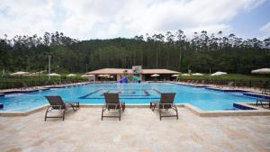 a large swimming pool with chairs and umbrellas at Hotel Fazenda Casarão do Vale in Massaranduba
