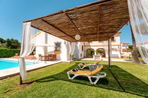 Un patio trasero con pérgola y piscina. en Villa La Caleta - Private Pool and Garden, en Islantilla