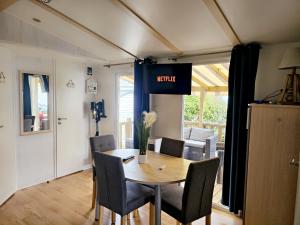 einen Esstisch mit Stühlen und ein Schild mit Trägheit in der Unterkunft Évasion océanique : Mobil-home dans un camping 4* à 50m de l'océan in La Bétaudière