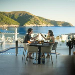 Parque Nereida Suites Hotel في كالا راتخادا: يجلس رجل وامرأة على طاولة مع أكواب