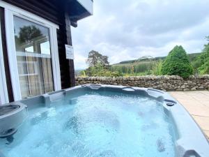 una bañera de hidromasaje en el patio trasero de una casa en Kaoglen-GrandSuite-Hot Tub-Pitlochry-Dunkeld-Pet Friendly en Balnald