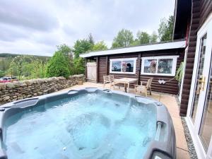 uma banheira de hidromassagem no pátio de uma casa em Kaoglen-GrandSuite-Hot Tub-Pitlochry-Dunkeld-Pet Friendly em Balnald