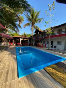a blue swimming pool in front of a building at Pousada Mutary in Santa Cruz Cabrália