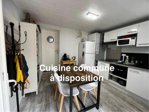 eine Küche mit weißen Schränken sowie einem Tisch und Stühlen in der Unterkunft Villa Herbert, Chambres d'Hôtes et Gîte in Andernos-les-Bains