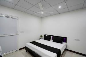 een slaapkamer met een bed in een witte kamer met een plafond bij SPOT ON Hotel Blu Moon in Noida