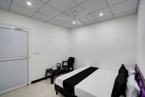 een slaapkamer met een bed en een witte muur bij SPOT ON Hotel Blu Moon in Noida