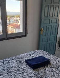 a blue pillow on a bed in a room with a window at Appartement port Nautic 5 Empuria in Empuriabrava
