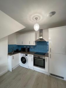 a kitchen with white cabinets and a washer at 1 Bedroom Flat in Bedford in Bedford +5 photos