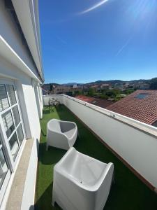 balkon z 2 białymi krzesłami na trawie w obiekcie Avenida 37 w mieście Caldas de Reis