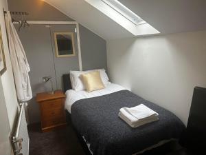 a small bedroom with a bed and a skylight at The London Inn in Cheltenham