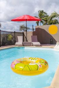 a swimming pool with a red umbrella and an inflatable at Maison charmante à Saint-François + Piscine partagée in Saint-François