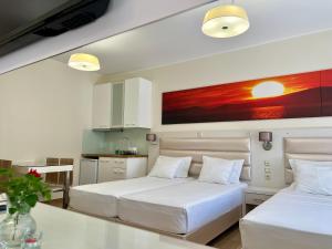 two beds in a white room with a kitchen at Valentinos House in Parga +96 photos