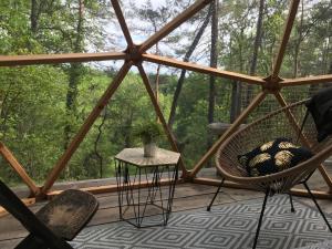 a screened in porch with a chair and a table at Arborea, nuits insolites au cœur de la forêt in Montignac
