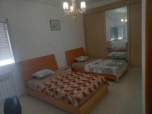 a bedroom with two beds and a mirror at Residence Amira in Monastir