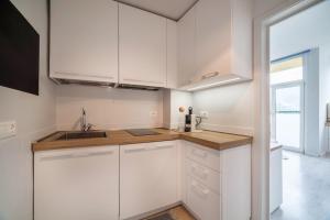 a kitchen with white cabinets and a sink at Nuvola 5th Floor in Merano